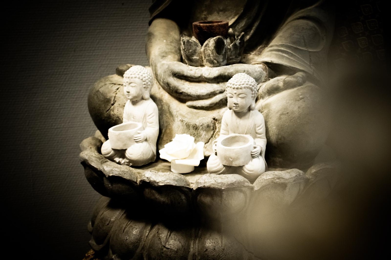 Decorative Buddha statues holding small bowls and candles